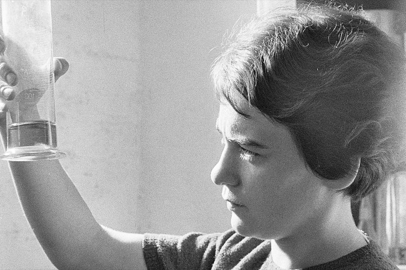 Historische Schwarz-Weiss-Aufnahme der Tochter des Firmengründers, die einen Messzylinder prüft.