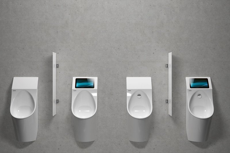 Vier moderne Urinale an einer Betonwand, teilweise mit integrierten Spülsystemen und Trennwänden.