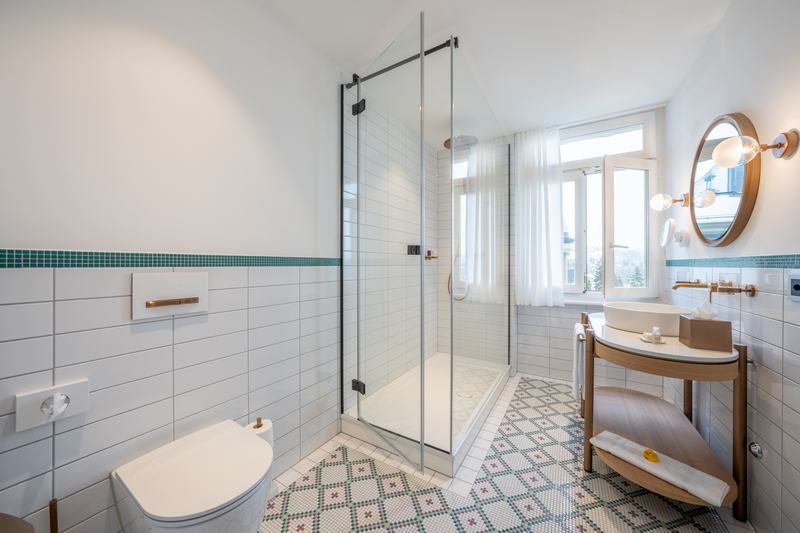 Modernes Badezimmer mit begehbarer Dusche, WC, Waschbecken und gemustertem Fliesenboden