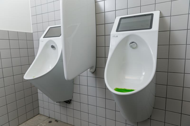 Moderne Urinale in einem öffentlichen Sanitärraum mit gefliesten Wänden