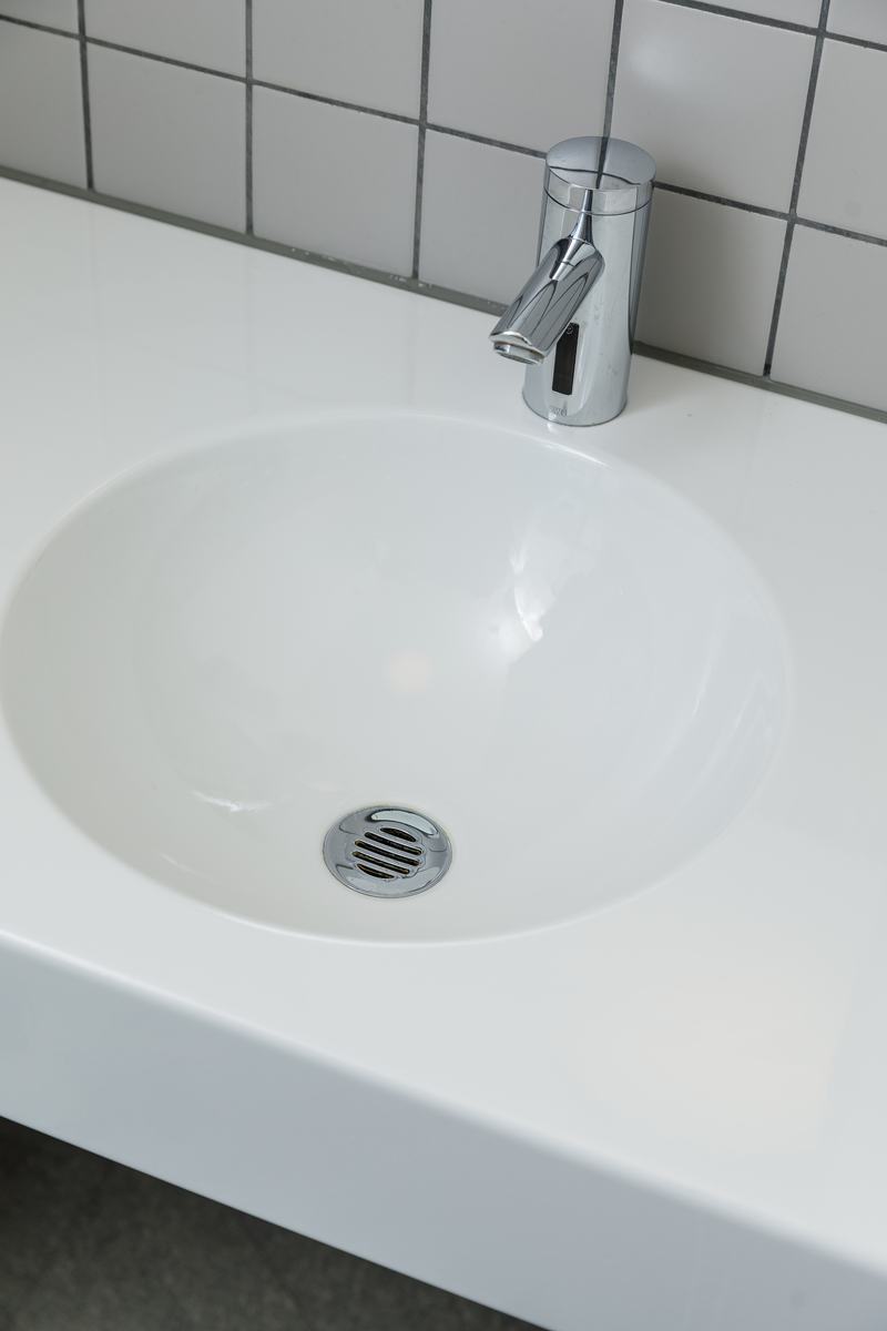 Weisses Waschbecken mit verchromter Armatur und schlichter Fliesenwand