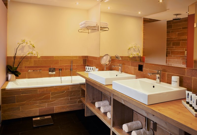 Modernes Badezimmer mit Doppelwaschbecken, Holzwaschtisch und Badewanne mit Natursteinverkleidung