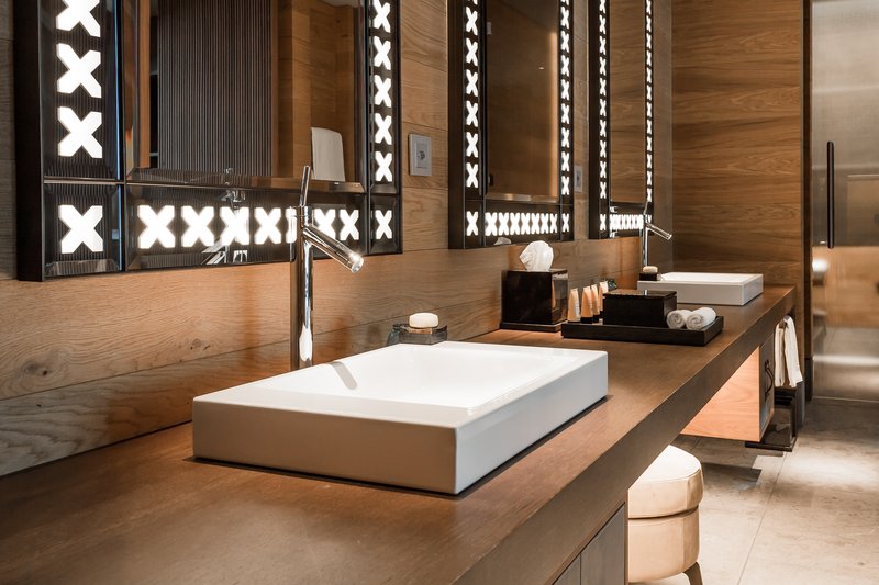Modernes Badezimmer mit Aufsatzwaschbecken, Holzoberflächen und beleuchtetem Spiegel