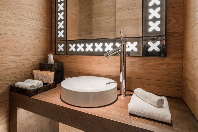Modernes Badezimmer mit rundem Aufsatzwaschbecken, Holzoberflächen und beleuchtetem Spiegel