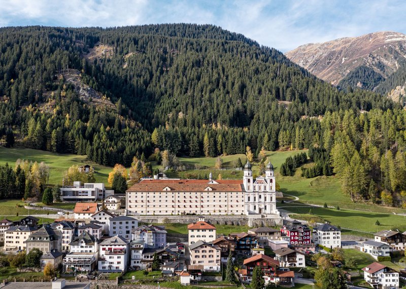 Kloster Disentis in Graubünden, eingebettet in alpine Landschaft mit Dorf und Bergen
