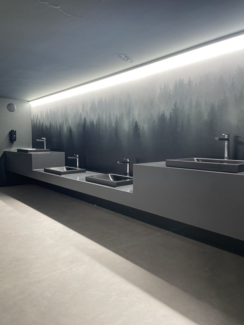 Modern gestalteter Waschraum mit minimalistischen Waschbecken und Wandgestaltung mit Waldmotiv
