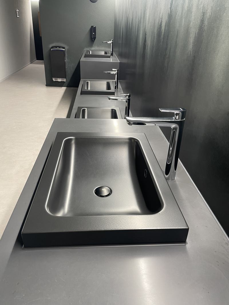 Moderner Waschraum mit Edelstahl-Waschbecken und minimalistischen Armaturen