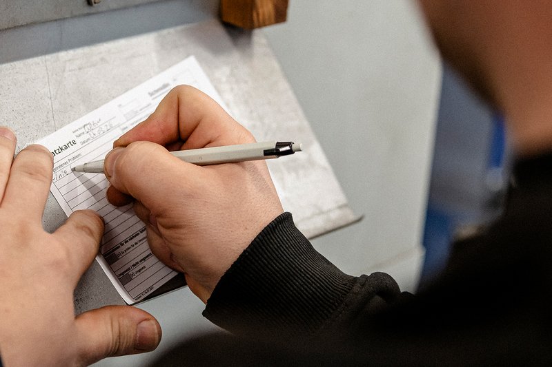 Mitarbeiter der Wilhelm Schmidlin AG füllt eine Schatzkarte mit einem Stift auf einem Klemmbrett aus