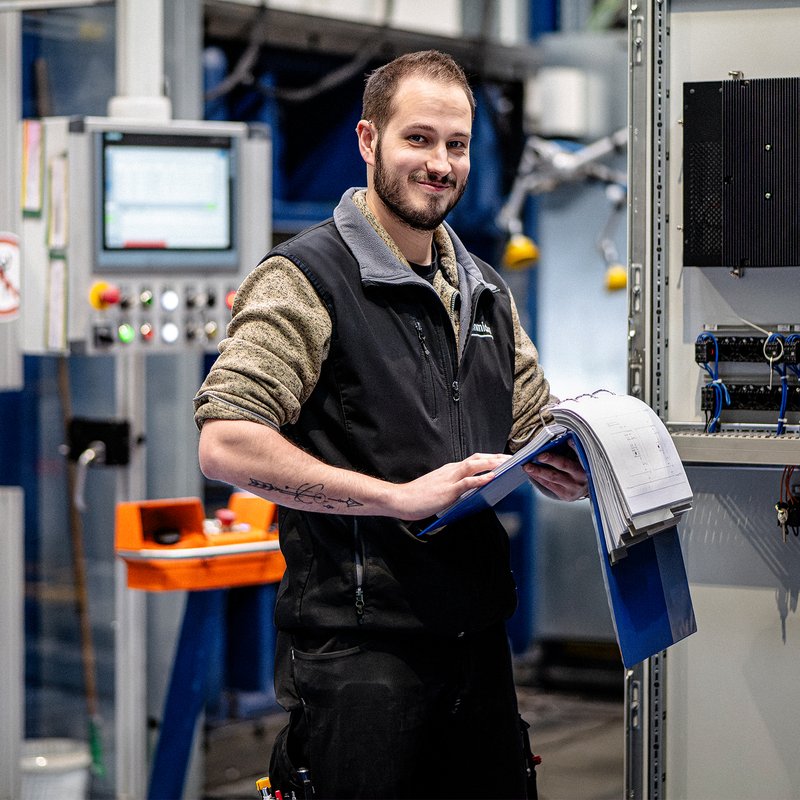 Mitarbeiter der Wilhelm Schmidlin AG überprüft Unterlagen und Produktionsdaten an einer Maschine