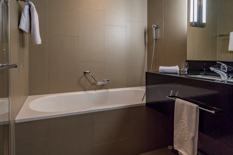 Modernes Badezimmer mit Badewanne, dunklem Waschtisch und schlichten Wandfliesen