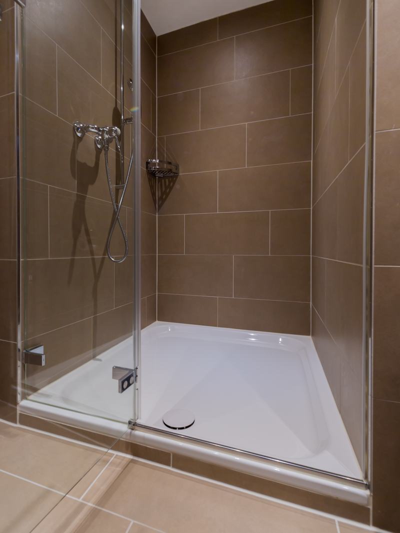 Moderne Dusche mit Glasabtrennung und braunen Wandfliesen
