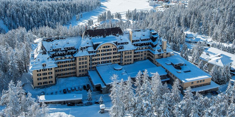 Luftaufnahme des Suvretta House in St. Moritz im Winter mit schneebedeckter Landschaft.