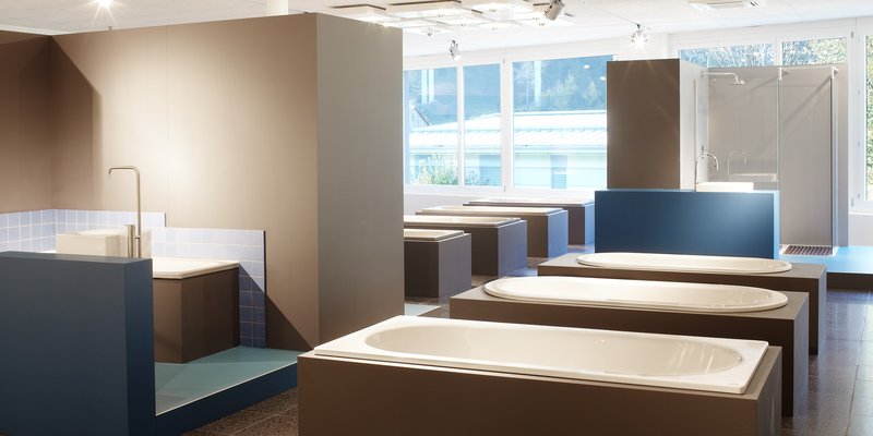 Moderne Badausstellung mit verschiedenen Badewannen und Duschen von Schmidlin, präsentiert in einem hellen Showroom mit stilvollem Design.
