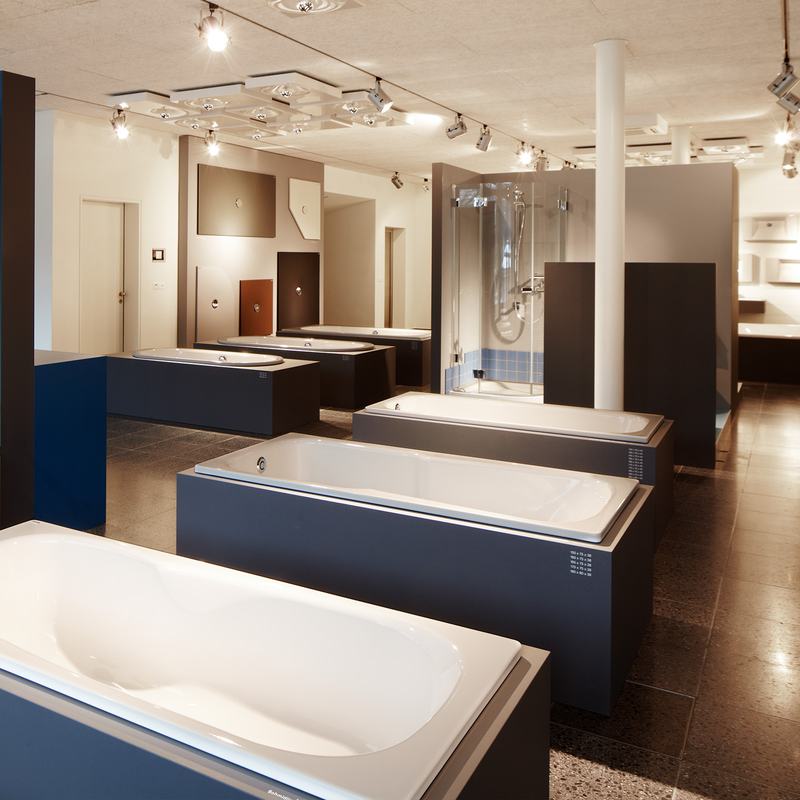 Moderne Badausstellung mit verschiedenen Badewannen und Duschen von Schmidlin, präsentiert in einem hellen Showroom mit stilvollem Design.
