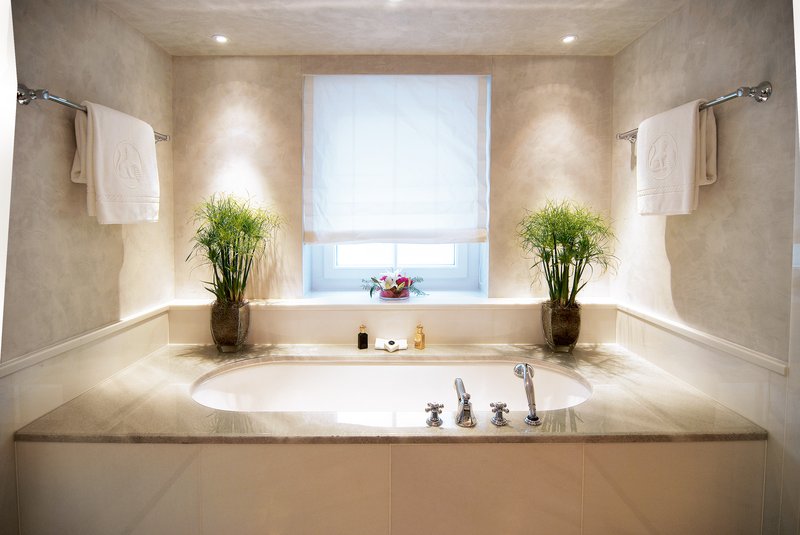 Elegantes Badezimmer mit eingelassener Badewanne, Natursteinoberflächen und dekorativen Pflanzen