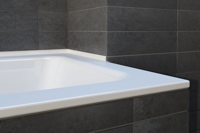 Schmidlin Teilzarge aus Stahl an einer Badewanne mit dunkler Wandverfliesung.