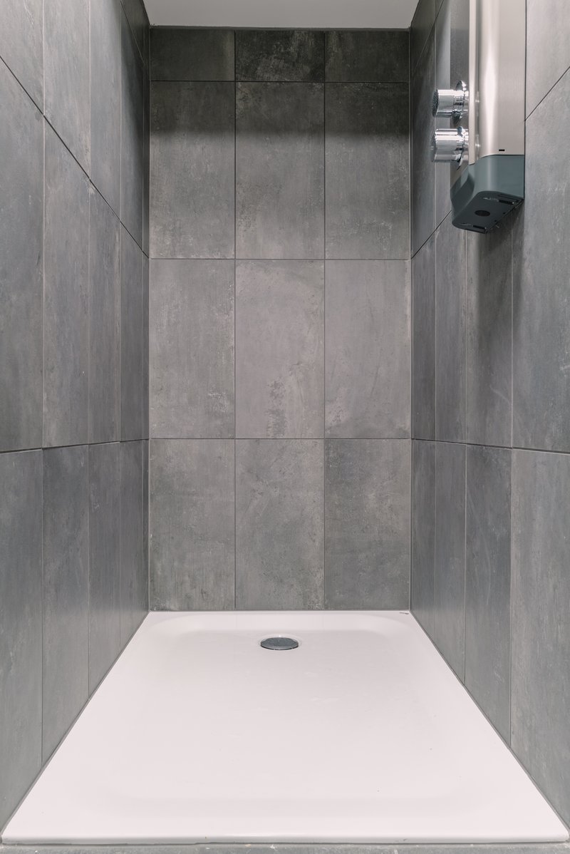 Moderne Dusche mit grossformatigen grauen Fliesen und minimalistischer Gestaltung