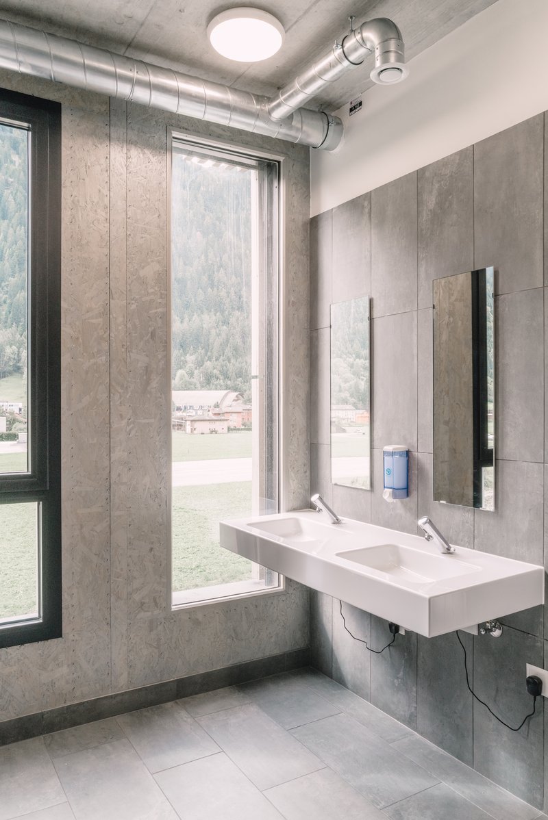 Moderner Waschraum mit Doppelwaschbecken, grossen Fenstern und Blick auf Berglandschaft