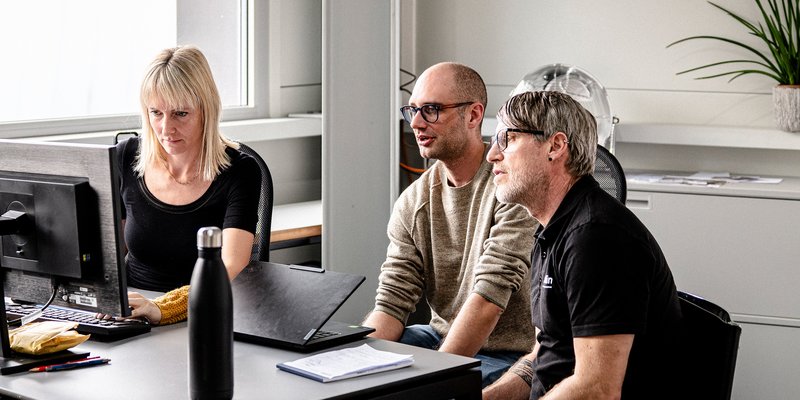 Mitarbeitende von Schmidlin arbeiten gemeinsam am Computer im Büro