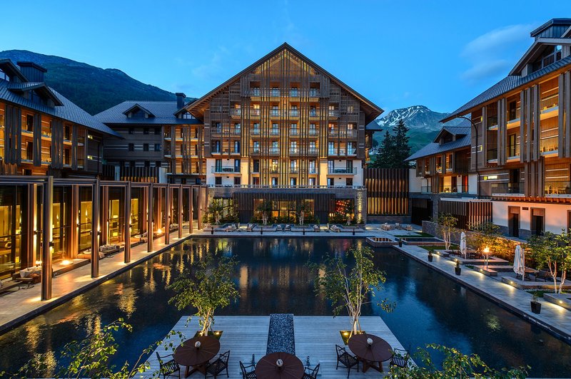 Luxuriöses Hotelresort bei Abenddämmerung mit beleuchtetem Gebäude, Pool und Terrasse