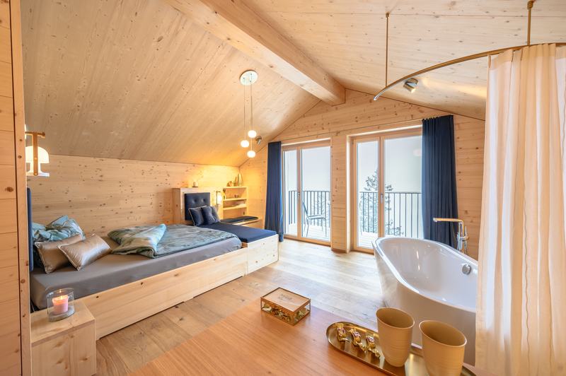 „Modernes Chalet-Schlafzimmer mit Holzdesign, freistehender Badewanne und Balkon mit Bergblick